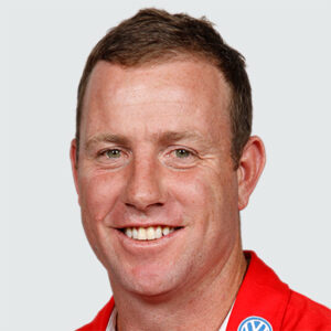 Head-and-shoulders portrait of a smiling man wearing a red polo with a Volkswagen logo on the collar
