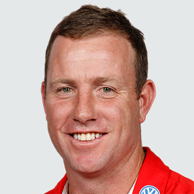 Head-and-shoulders portrait of a smiling man wearing a red polo with a Volkswagen logo on the collar